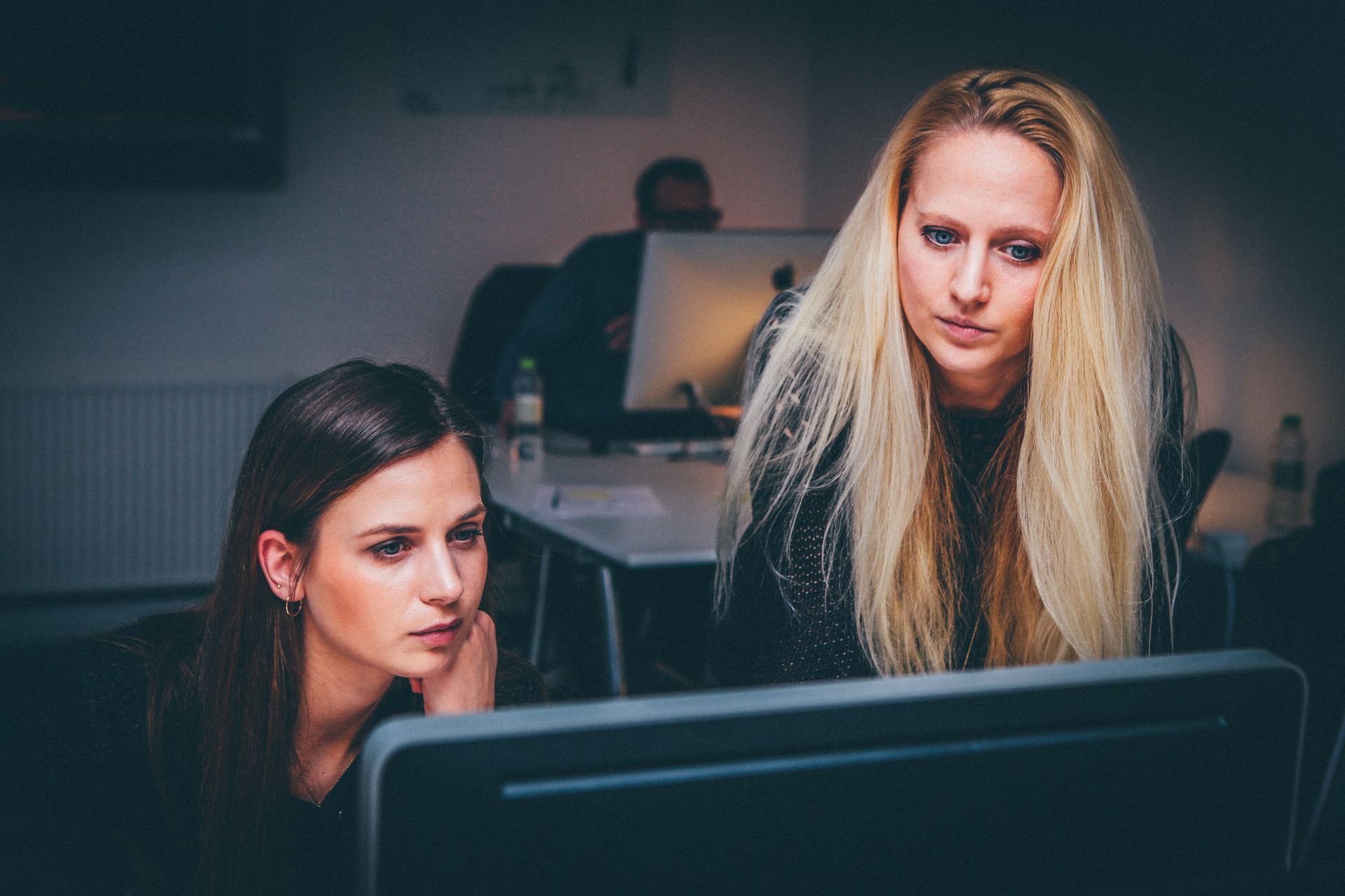 Photo sombre montrant deux femmes qui regardent un ordinateur. L'agence JVFlex a choisi cette photo pour imager la formation Améliorez votre communication sur les réseaux sociaux.